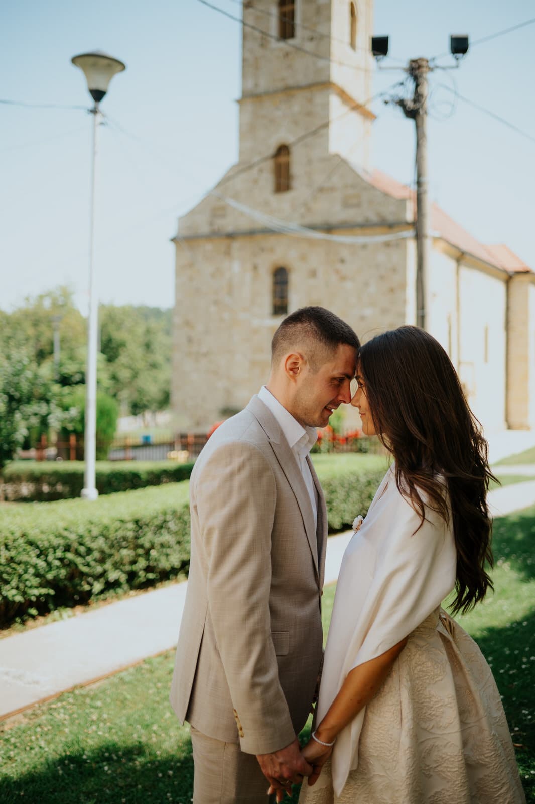 Mladenci se nežno dodiruju ispred crkve